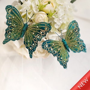Puede incluir: Dos mariposas verde azulado con detalles de purpurina dorada. Las mariposas tienen un diseño delicado e intrincado y son perfectas para añadir un toque de fantasía a cualquier proyecto de manualidades.