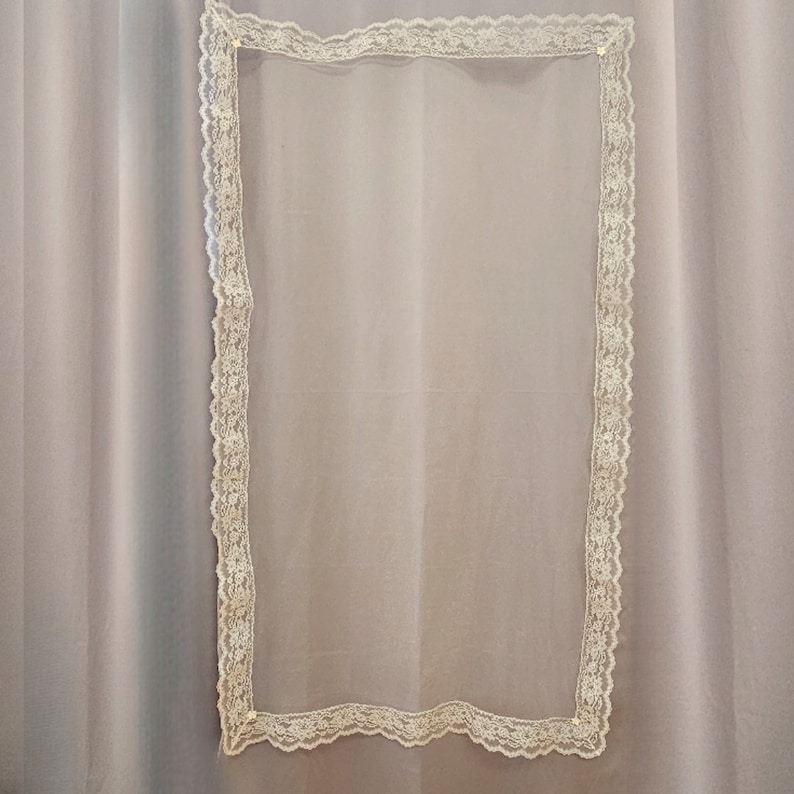 Puede incluir: Un rect&aacute;ngulo de tela blanca transparente con un borde de encaje blanco.