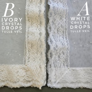Puede incluir: Dos velos de tul con ribete de encaje, uno marfil y otro blanco. Ambos velos tienen gotas de cristal y el texto "Crystal Drops Tulle Veil" est&aacute; escrito en cada velo.