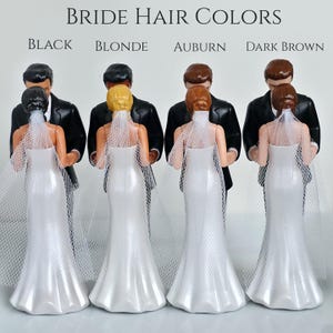 May include: Wedding cake toppers featuring a bride and groom. The brides have different hair colors: black, blonde, auburn, and dark brown. The brides wear white wedding dresses and veils, and the grooms wear black tuxedos. The text "Bride Hair Colors" is at the top.