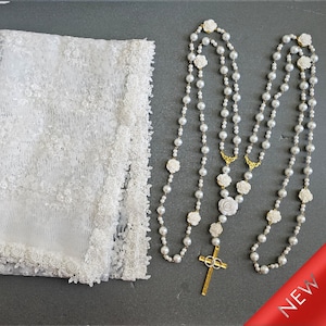 Può includere: Velo in pizzo bianco e un rosario di perle bianche con una croce dorata e dettagli di rose bianche. Il rosario è nuovo.
