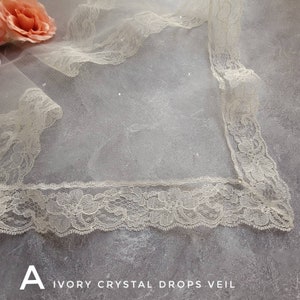 May include: Ivory bridal veil with a delicate floral lace trim and crystal embellishments. The veil is made of soft tulle and has a square shape.
