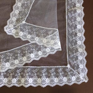 May include: White lace trim with a floral pattern. The lace is delicate and intricate, with a scalloped edge. The lace is perfect for adding a touch of elegance to any project.