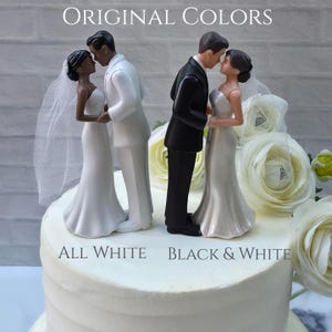 May include: Wedding cake toppers featuring a bride and groom in two color schemes: all white and black and white. The toppers show the couple in an embrace, with the text "ORIGINAL COLORS", "ALL WHITE", and "BLACK & WHITE".