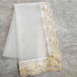 May include: White sheer veil with gold lace trim. The lace has a floral pattern and is on all four sides of the veil.