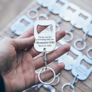 A hand holding a personalized stainless steel bottle opener keychain, with a clear view of the engraved thank you message and attached keyring, ready for use.