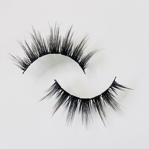 Op de afbeelding: Een paar zwarte valse wimpers met een natuurlijke, vederlichte uitstraling. De wimpers zijn gebogen en hebben een dun bandje.