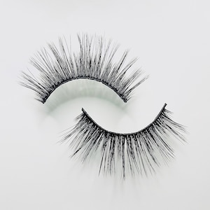 May include: A pair of black false eyelashes with a natural, wispy look. The lashes are curved and have a black band.