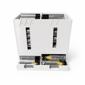 May include: A white battery organizer with compartments for AAA and AA batteries. The organizer is filled with various batteries, including Energizer Industrial batteries. The front of the organizer has the battery type labels.
