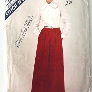 Könnte beinhalten: Ein Schnittmusterumschlag mit der Aufschrift 8266 Stitch 'N Save Größe A (6-8-10), der eine weiße langärmelige Bluse mit einer großen Schleife am Kragen und einen einfarbigen roten bodenlangen Rock mit einem dünnen Gürtel zeigt.