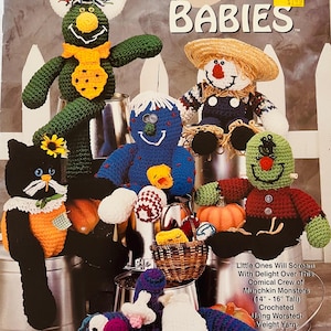 May include: A crochet pattern book called "Boo Babies" showcasing several handmade crochet monster dolls. The dolls are in various colours and designs, including a green monster, a scarecrow, and a black cat. The book is designed by Estella Whitford.