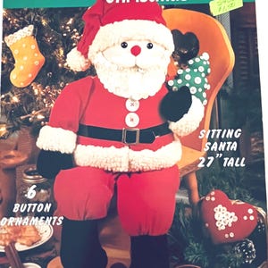 Może przedstawiać: Wzór McCall's na świąteczną lalkę Świętego Mikołaja, zatytułowany "Cute-as-a-Button". Święty Mikołaj jest czerwono-biały, z czarnymi butami i czarnym paskiem. Wzór zawiera instrukcje wykonania Świętego Mikołaja o wysokości 68.58 cm i sześciu ozdób z guzików.