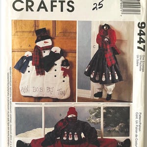 May include: McCall's Crafts pattern featuring snowman designs. The pattern includes instructions for creating various snowman-themed items, such as a wall hanging, a dress, and a figure in a split. The designs incorporate red, black, and white colors.