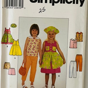 Può includere: Modello di cucito Simplicity numero 8583, taglia AA 3, 4, 5, 6. Il modello include istruzioni per realizzare un vestito, una maglietta, pantaloni e un cappello. Il modello è illustrato con una ragazza che indossa un vestito verde e rosa, una ragazza che indossa un vestito giallo e una ragazza che indossa una maglietta bianca e pantaloni arancioni.