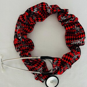 May include: A red and black stethoscope holder with a pattern of a cartoon character with the text "Harley Quinn".
