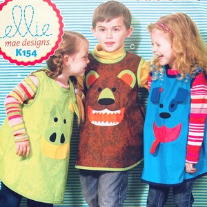 May include: Three children wearing animal-themed aprons. The aprons are green with a pig face, brown with a bear face, and blue with a dog face. The aprons are part of a sewing pattern from "ellie mae designs" K154.