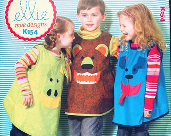 May include: Three children wearing animal-themed aprons. The aprons are green with a pig face, brown with a bear face, and blue with a dog face. The aprons are part of a sewing pattern from "ellie mae designs" K154.