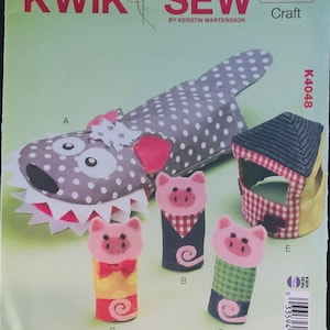 May include: A sewing pattern titled "KWIK SEW K4048 Craft" featuring various fabric crafts. The image shows a shark-shaped pillow, a house-shaped item, and several pig-shaped finger puppets with different outfits. The background is light green.