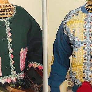 May include: Two quilted jackets on display. One is dark green with patchwork accents and scalloped edges. The other is blue with a yellow and white geometric pattern and red heart details. Both are displayed on wicker mannequins.