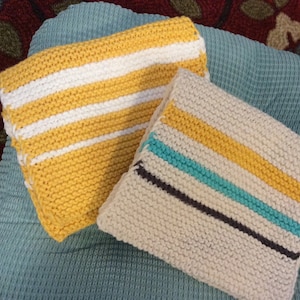 May include: Two knitted dishcloths with striped patterns. One dishcloth is yellow with white stripes, and the other is white with yellow, turquoise, and gray stripes.