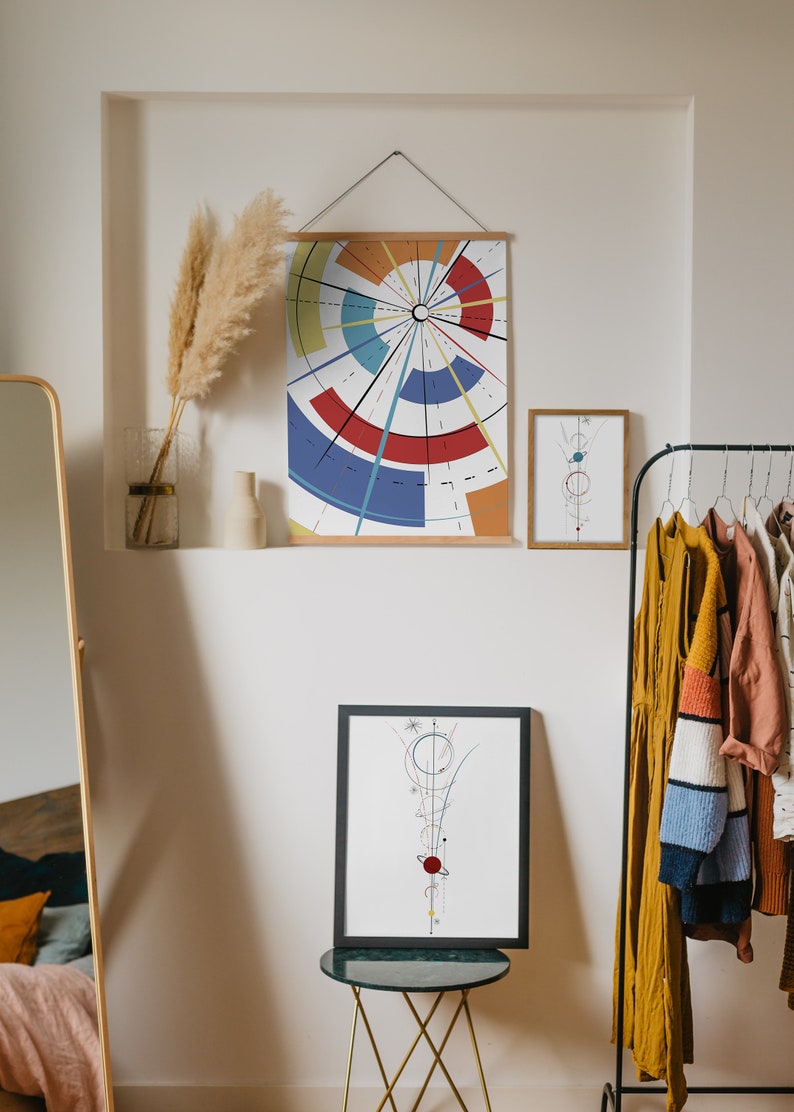 May include: A selection of framed art prints with geometric designs. The largest print displays a colourful radial pattern, while the smaller prints feature abstract line art. A clothes rail with various garments is visible on the right.