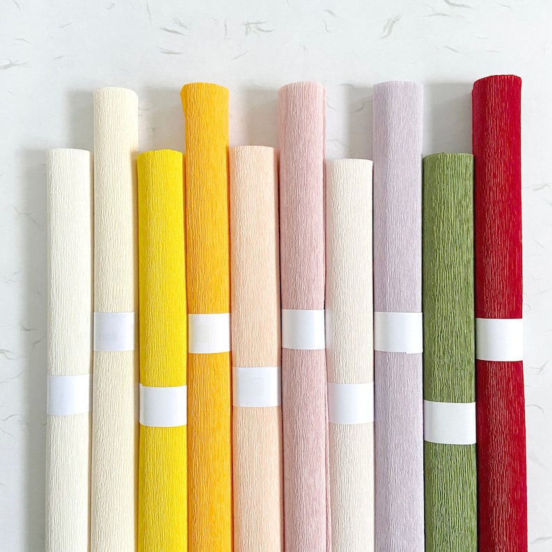 Peut inclure: Une collection de papier cr&eacute;pon roul&eacute; de diff&eacute;rentes couleurs : cr&egrave;me, jaune, p&ecirc;che, rose, lavande, vert et rouge. Chaque rouleau est maintenu par une bande blanche. Le papier a une surface textur&eacute;e et froiss&eacute;e, id&eacute;ale pour les loisirs cr&eacute;atifs.