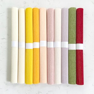 Peut inclure: Plusieurs rouleaux de papier cr&eacute;pon de couleurs vari&eacute;es : cr&egrave;me, jaune, p&ecirc;che, lavande, vert et bordeaux. Chaque rouleau est maintenu par une bande blanche. Le papier pr&eacute;sente une surface textur&eacute;e, id&eacute;al pour les loisirs cr&eacute;atifs.