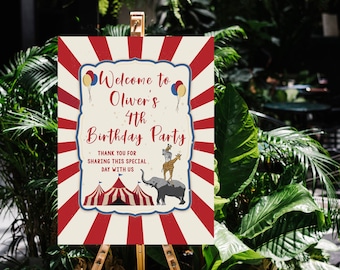 May include: A wooden easel displays a party sign with a circus theme. The sign reads "Welcome to Oliver's 4th Birthday Party." Red and white stripes frame the text, with illustrations of circus animals and a tent.