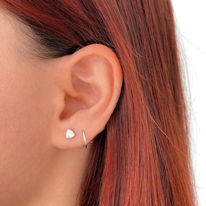 Peut inclure: Gros plan sur l'oreille d'une personne avec un petit piercing en diamant et un anneau en argent.