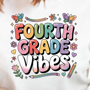 May include: White t-shirt featuring the text "FOURTH GRADE VIBES" in colourful bubble letters, adorned with butterflies, flowers, and pencils. The shirt is a casual style, suitable for school or everyday wear.