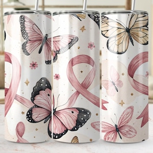 May include: A white tumbler with a watercolour design of pink butterflies, ribbons, and small flowers. The butterflies have black and pink details. Gold stars and dots complete the design. The tumbler has a silver straw.
