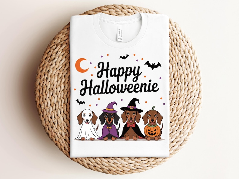 May include: White t-shirt featuring the text "Happy Halloweenie" with a crescent moon and bats. Below the text are four dachshunds dressed in Halloween costumes, including a ghost, witch, and pumpkin.
