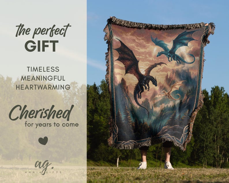 May include: A tapestry blanket featuring a fantasy scene with three dragons soaring over a mountainous landscape. The blanket has a fringed edge and is held up against a blue sky. The text on the left side says "The perfect GIFT".
