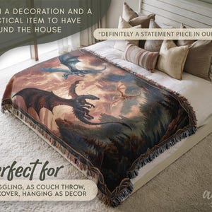 May include: A woven throw blanket featuring a fantasy dragon scene in shades of brown, blue, and red. The blanket is fringed and displayed on a bed with white linens. Text on the image reads, "Definitely a statement piece in our home."