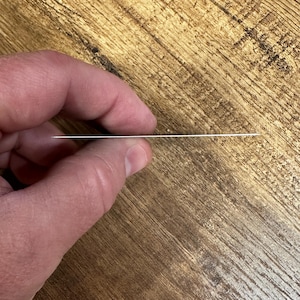 May include: A close-up of a silver metal card being held by a hand. The card is thin and rectangular.