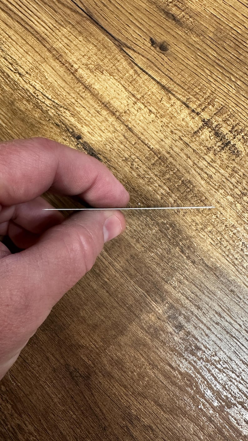 May include: A close-up of a silver metal card being held by a hand. The card is thin and rectangular.