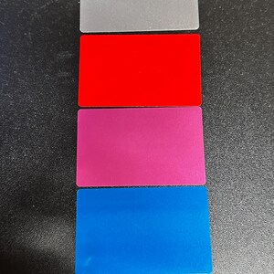 May include: Six rectangular cards stacked vertically, each a different colour: gold, silver, red, pink, blue, and black.