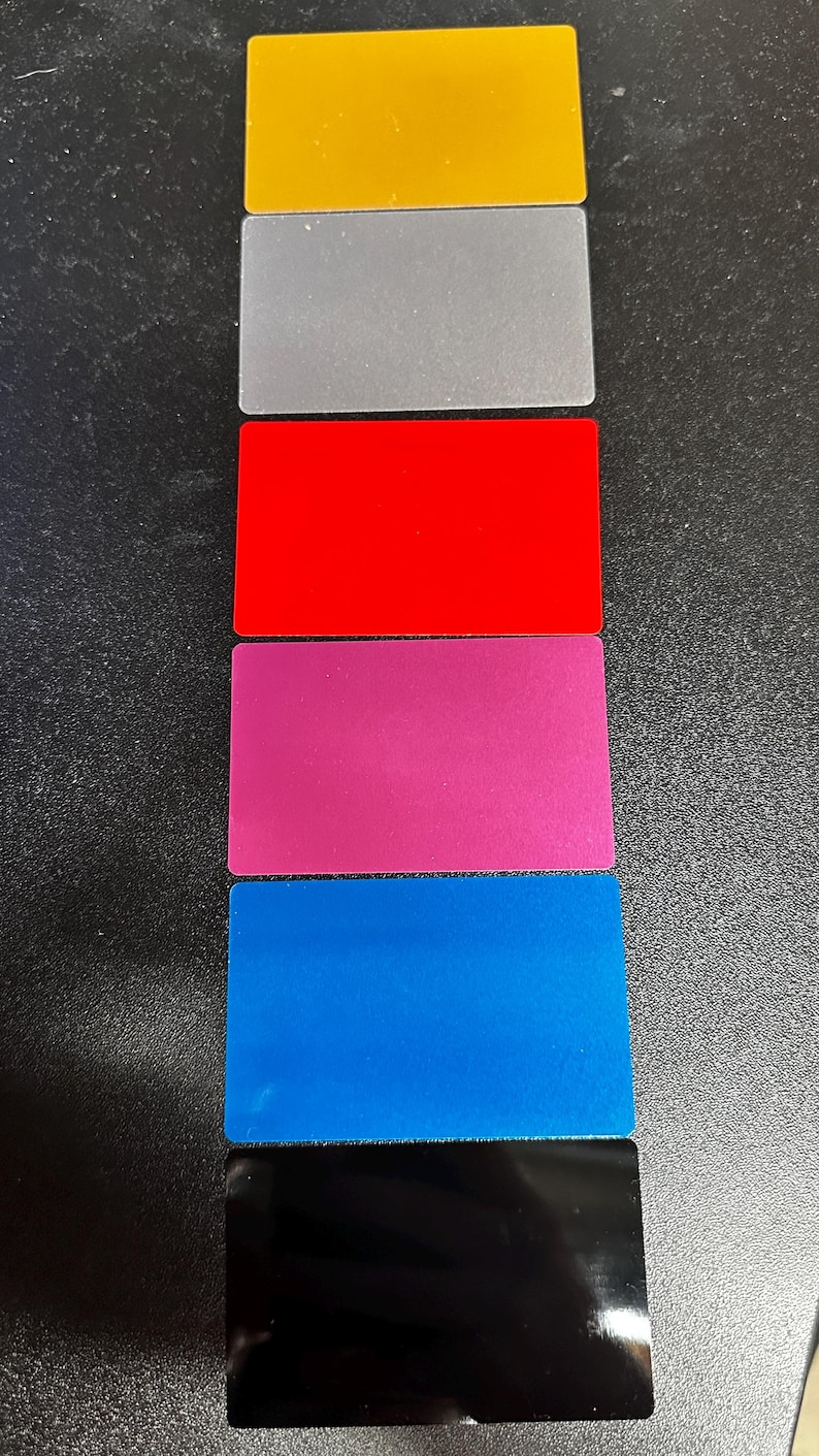 May include: Six rectangular cards stacked vertically, each a different colour: gold, silver, red, pink, blue, and black.