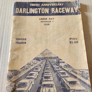 May include: A vintage 1959 Darlington Raceway souvenir program with a cream-colored cover featuring blue text and a blue illustration of race cars on a track. The text reads Tenth Anniversary, Darlington Raceway, Labor Day, September 7, 1959.