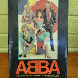 May include: A black VHS tape box featuring the music group ABBA. The cover displays a photograph of the four members against a colorful circular background. The text reads ABBA, ABBA IS THE GREATEST POP BAND OF THE LAST TEN YEARS, and monterey home video.