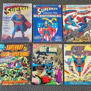 Puede incluir: Una colección de cómics vintage de DC Comics con Superman, Superboy y Batman. Las portadas muestran ilustraciones vibrantes de superhéroes en acción, con títulos como "Superman Salutes the Bicentennial" y "The Battle of the Century."