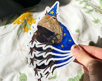 May include: A set of five stickers featuring a cartoon toad wearing a blue wizard hat with gold stars. The toad is holding a staff and has a friendly expression.
