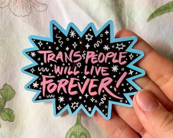 Puede incluir: Una pegatina con fondo negro y borde azul dentado. La pegatina tiene el texto "TRANS PEOPLE WILL LIVE FOREVER!" en rosa y blanco. El fondo está decorado con estrellas blancas y otras formas.