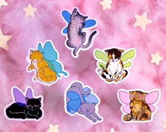 May include: Six colorful cat stickers with fairy wings. The cats are in various poses and have different colored fur. The stickers are on a pink background.
