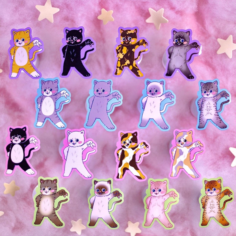 Op de afbeelding: Een set van 14 kleurrijke katten stickers met verschillende poses en uitdrukkingen. De stickers zijn op een roze achtergrond met witte sterren.