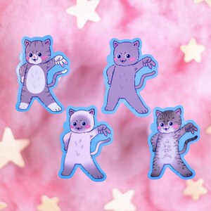 Op de afbeelding: Vier kleurrijke katten stickers met blauwe contouren. Elke kat staat in een andere pose met een speelse uitdrukking. De stickers zijn op een roze achtergrond met witte sterren.