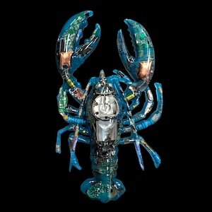 May include: A blue lobster sculpture made from recycled circuit boards and electronic components. The crustacean has a transparent body, revealing the internal hardware. Copper accents and a shiny silver component are visible.