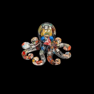 May include: A clear resin octopus figurine embedded with various electronic components, including colorful resistors, circuit boards, and two bright blue spherical eyes. The internal hardware is visible through the transparent material.