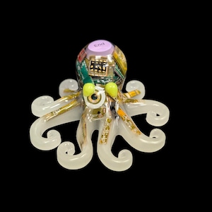 May include: A translucent octopus figurine crafted from resin, featuring embedded green and gold circuit board components throughout its body and eight curled tentacles. A light purple keyboard key labeled End sits atop the head, with two bright yellow beads serving as eyes.