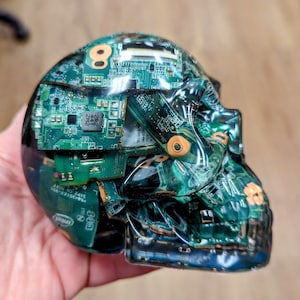May include: A clear resin skull filled with green circuit boards. The skull is a decorative object and is a unique piece of art.